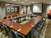 Meeting facility equipped with a white projector screen, table, and chairs.