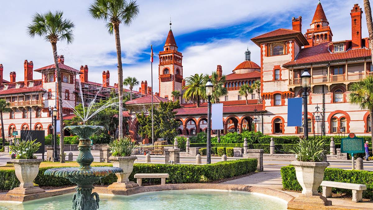 Historic building and fountain in St. Augustine, Florida with palm trees and blue sky.