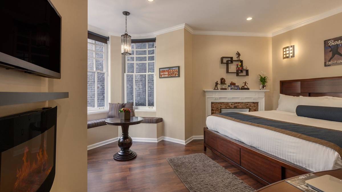 Interior suite with a bed, tv, fireplace, and table in a hotel in NYC