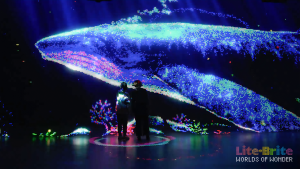two people looking at a big shark light artwork