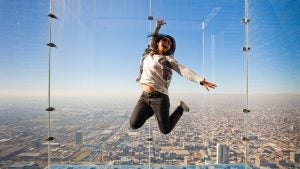woman jumping over an observatory deck, view of the city at the back